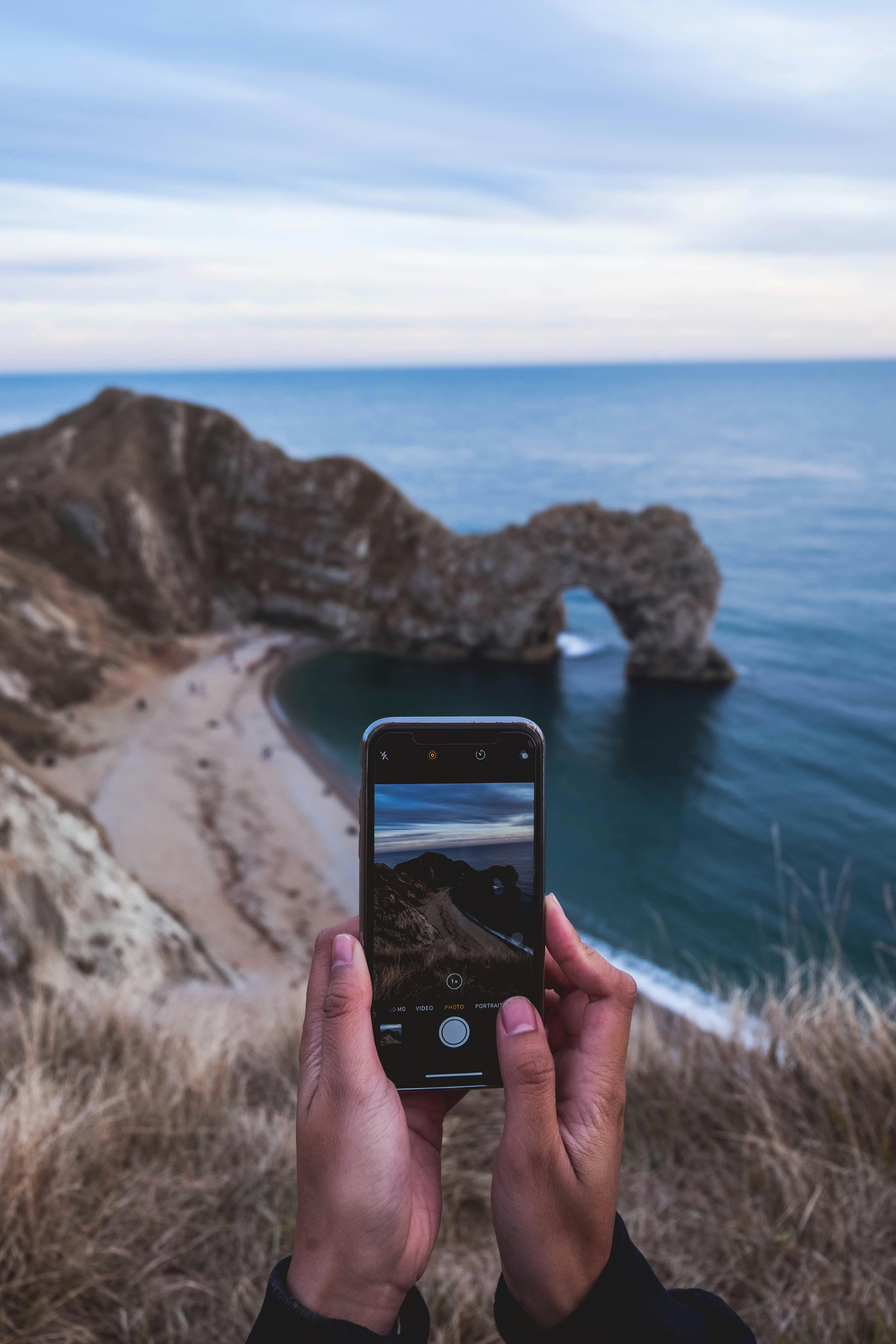 photo of person taking picture of seashore