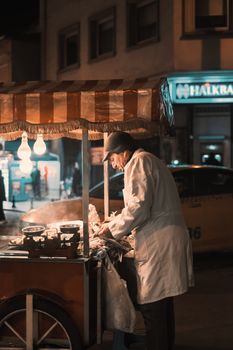 Street vendor selling food at night under warm lights in an urban setting.