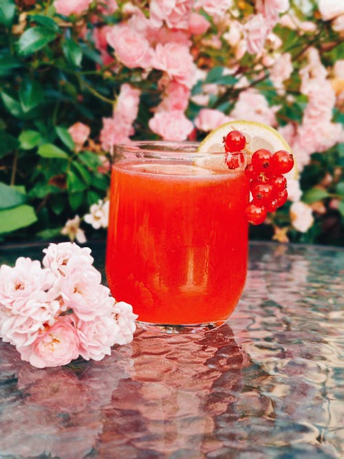 A Glass of Cocktail Drink Beside Pink Flowers