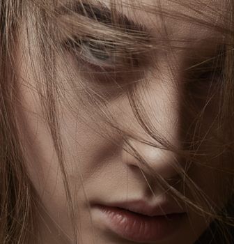 A compelling close-up of a woman with brown hair partially covering her face.