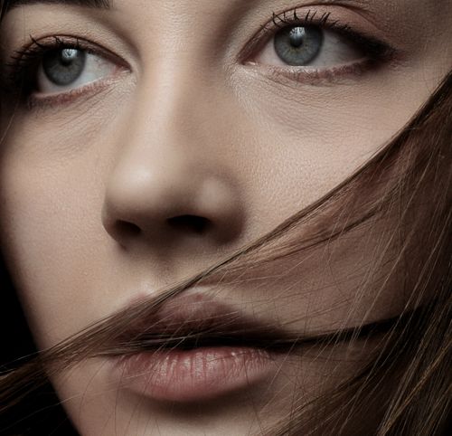 Free A detailed close-up portrait of a woman with piercing eyes and wind-swept hair. Stock Photo