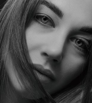 Close-up black and white portrait showcasing a woman's serene expression and captivating gaze.