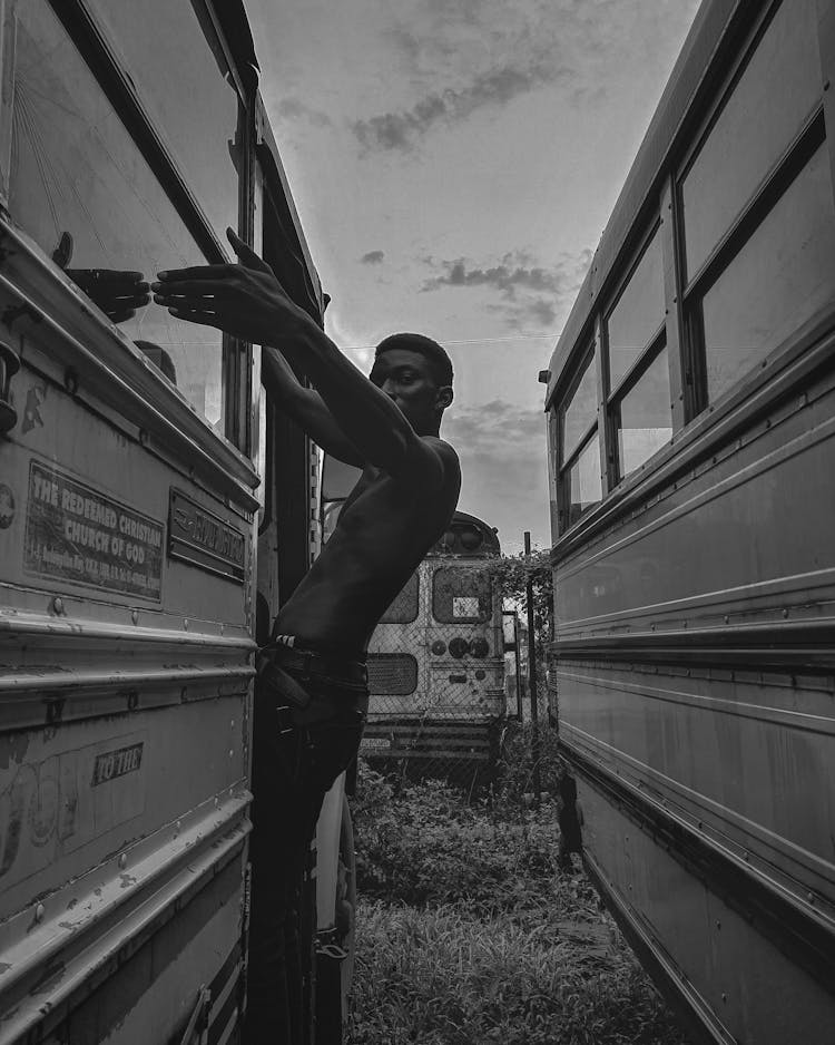 A Man Standing On The Side Of A Bus