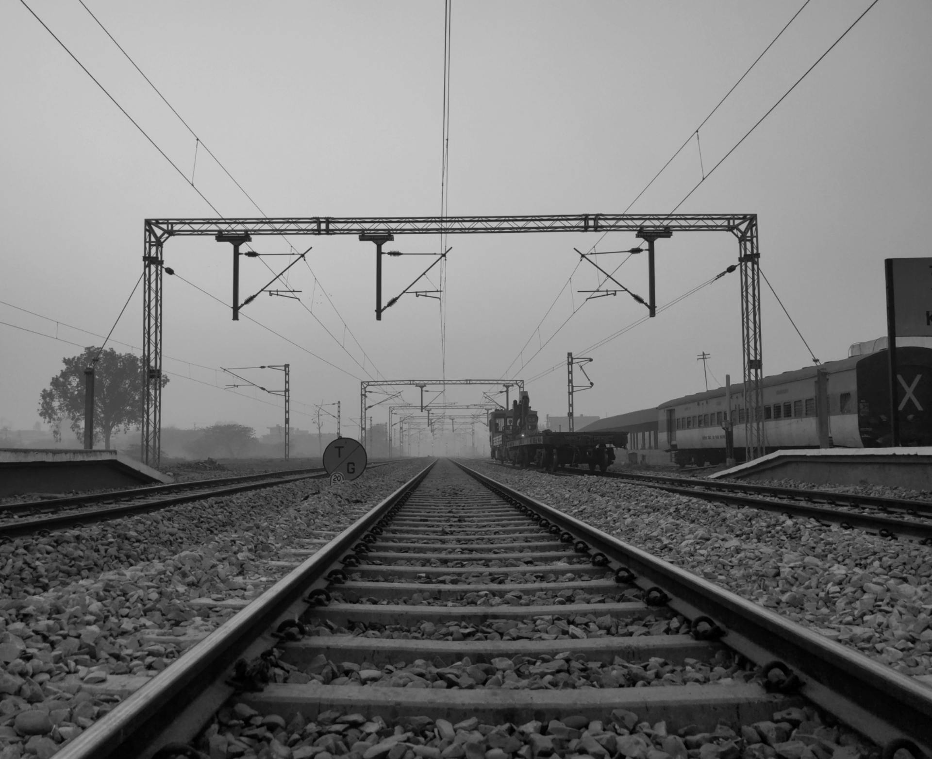 Monochrome view of railway tracks with electric lines in Delhi, India.