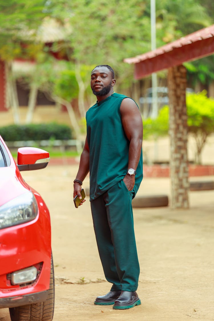 Man In Green Tank Top And Pants Standing Near The Car 