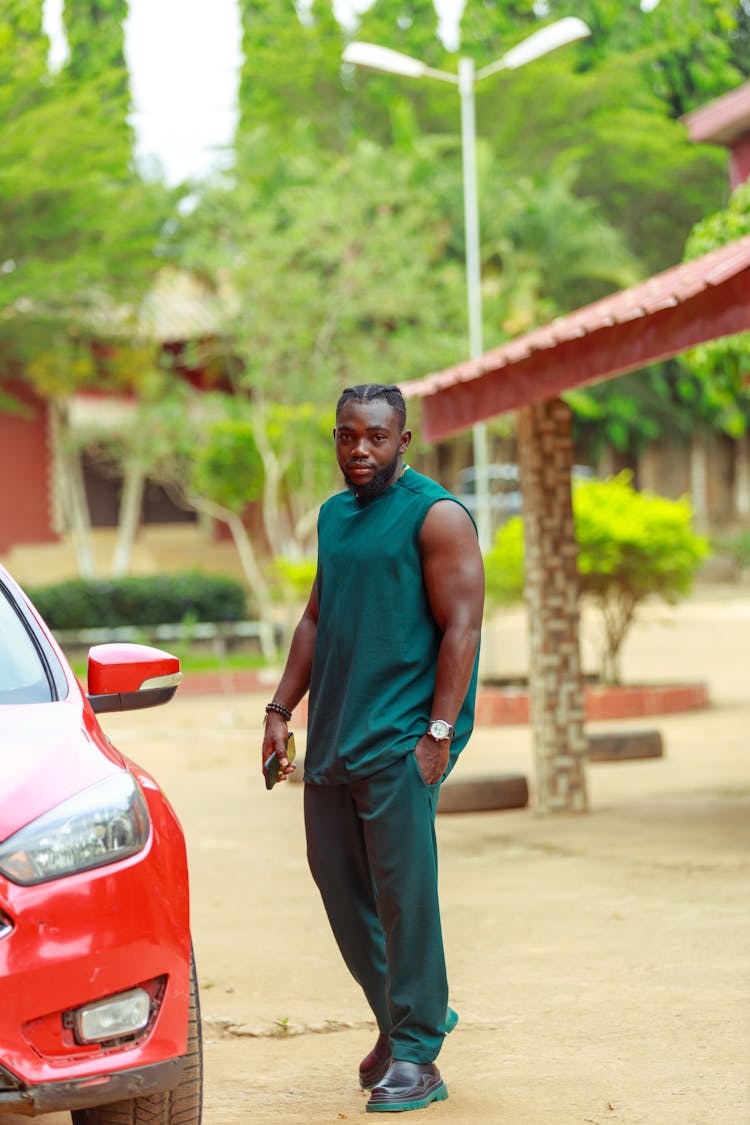 Young Man Standing By A Red Car 