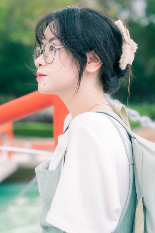 Free Side profile of a young woman with eyeglasses enjoying a serene outdoor view in spring. Stock Photo
