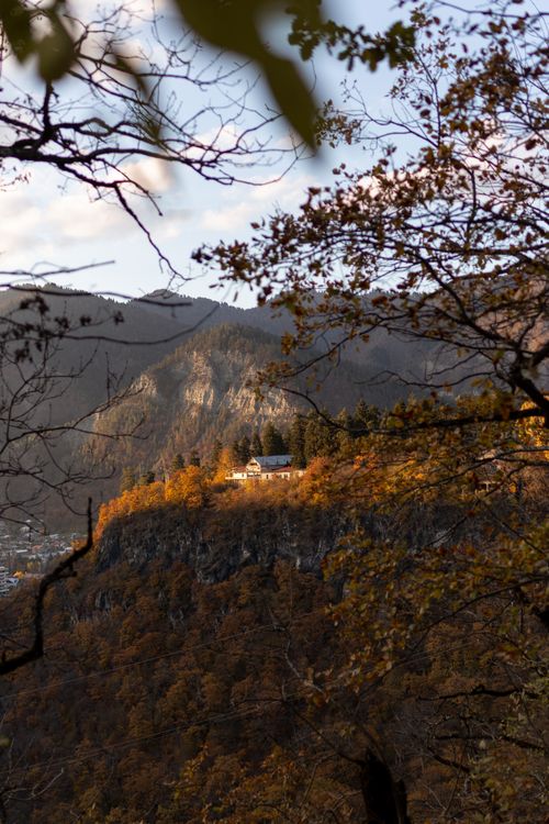 Free Picturesque autumn scene with house on a mountain cliff, surrounded by trees. Stock Photo
