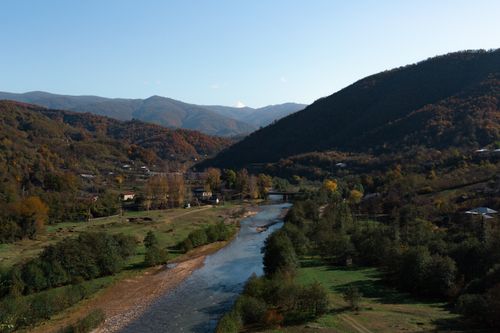 Free Explore the tranquil beauty of a river winding through a lush mountain valley. Stock Photo