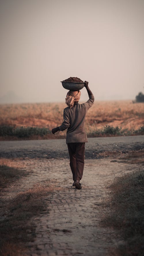 Man Walking and Carrying a Basket on his Head 