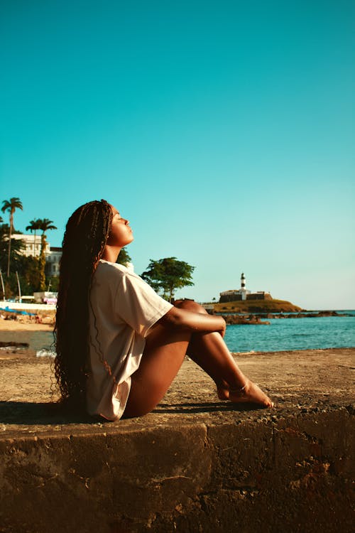 Woman Sitting by the Water and Soaking up the Sun 