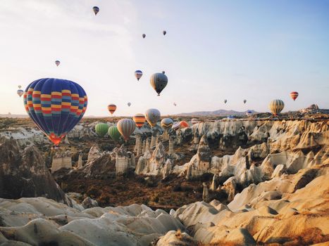 Colorful hot air balloons floating over Cappadocia's unique rock formations at sunrise.
