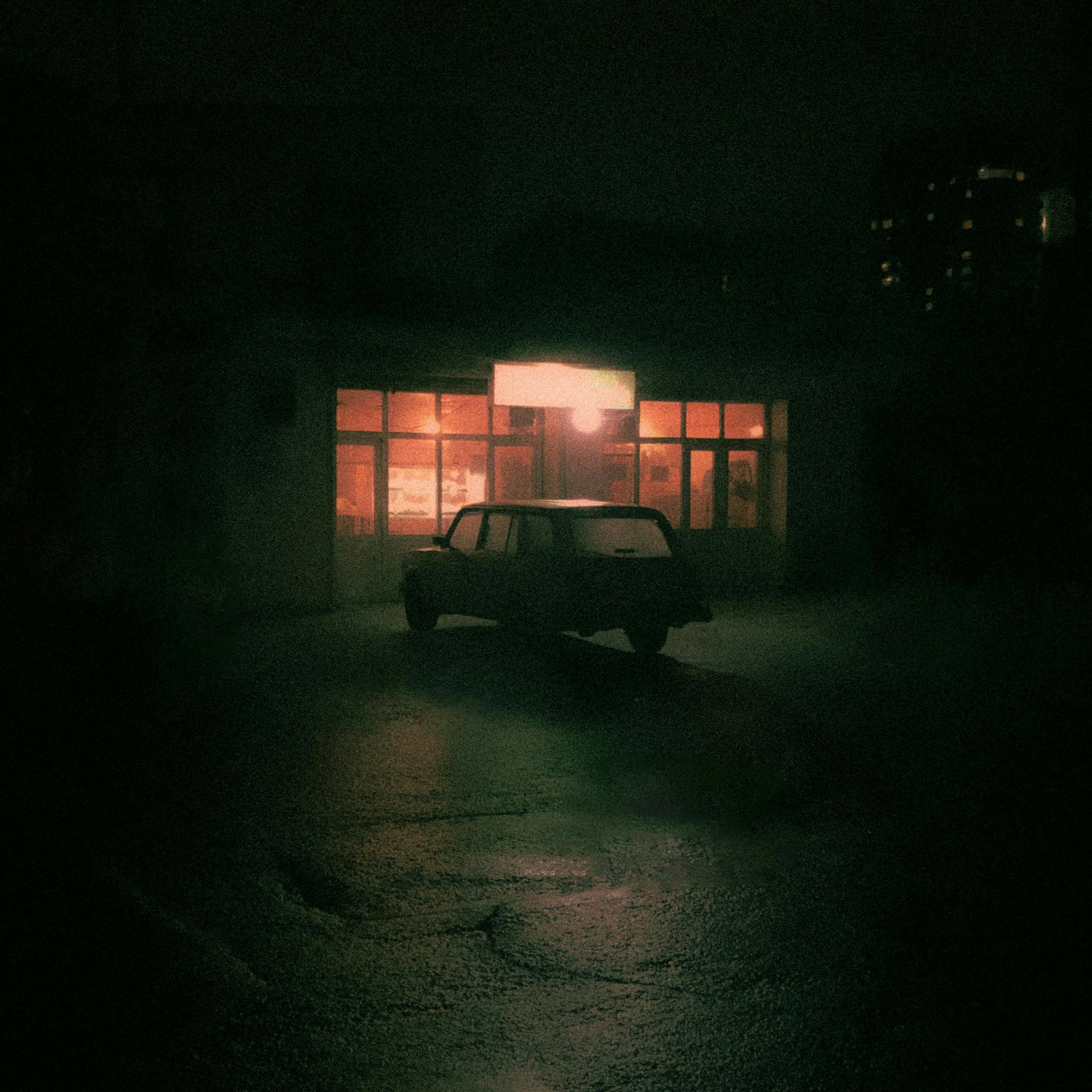 Moody night scene with a retro car in front of an illuminated Baku restaurant.