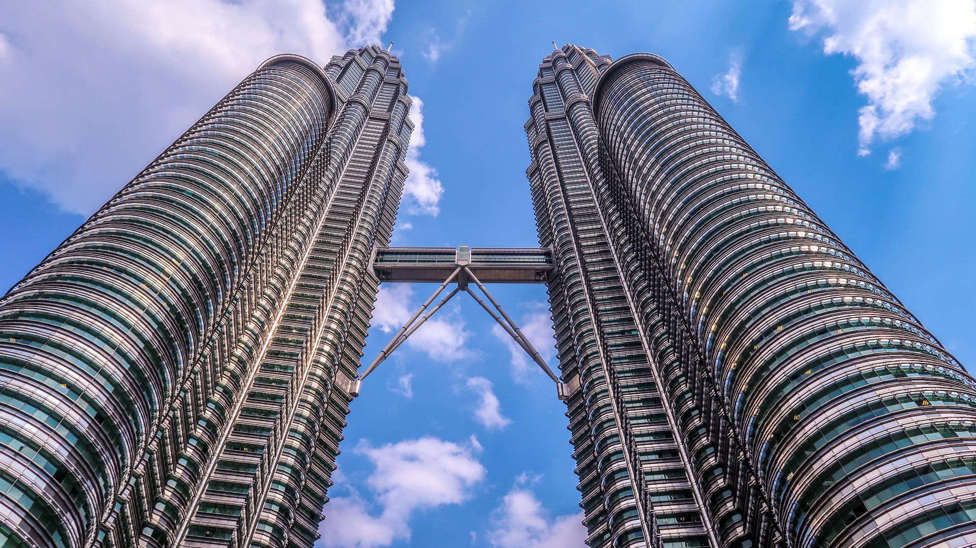Low angle view of the iconic Petronas Twin Towers in Kuala Lumpur, Malaysia, against a clear blue sky.