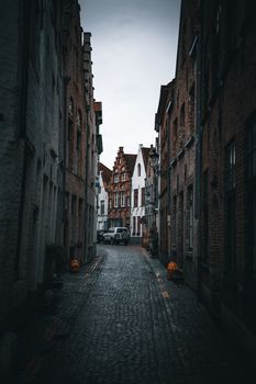 A moody view of a cobblestone alley lined with historic buildings in Bruges.