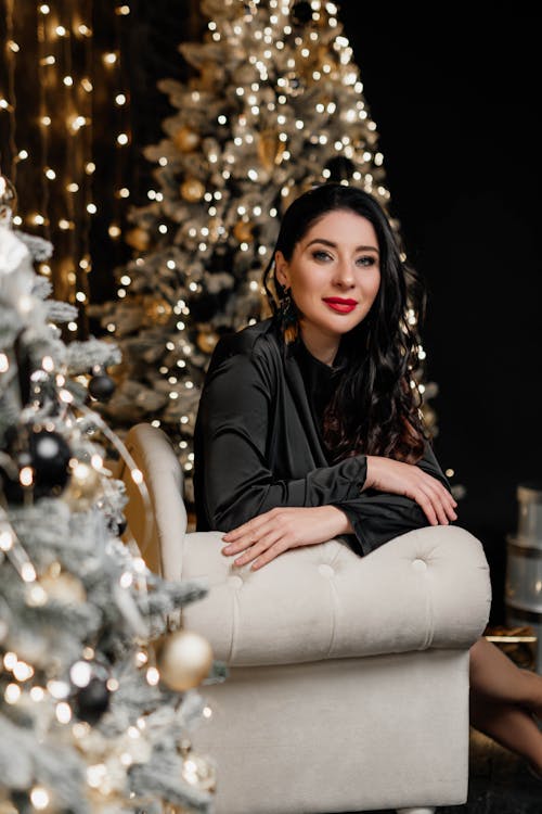 Free Woman Sitting in an Armchair by Christmas Trees Stock Photo