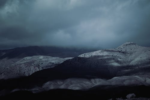 Landscape of Dark Mountains under a Cloudy Sky 