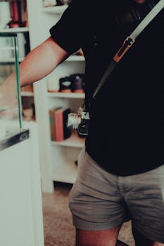 A man wearing shorts and t-shirt with camera indoors, close-up.