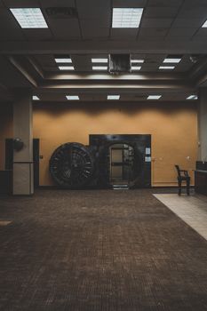 Photo by Connor Scott McManus A spacious bank interior showcasing a large, open vault door under a modern ceiling.