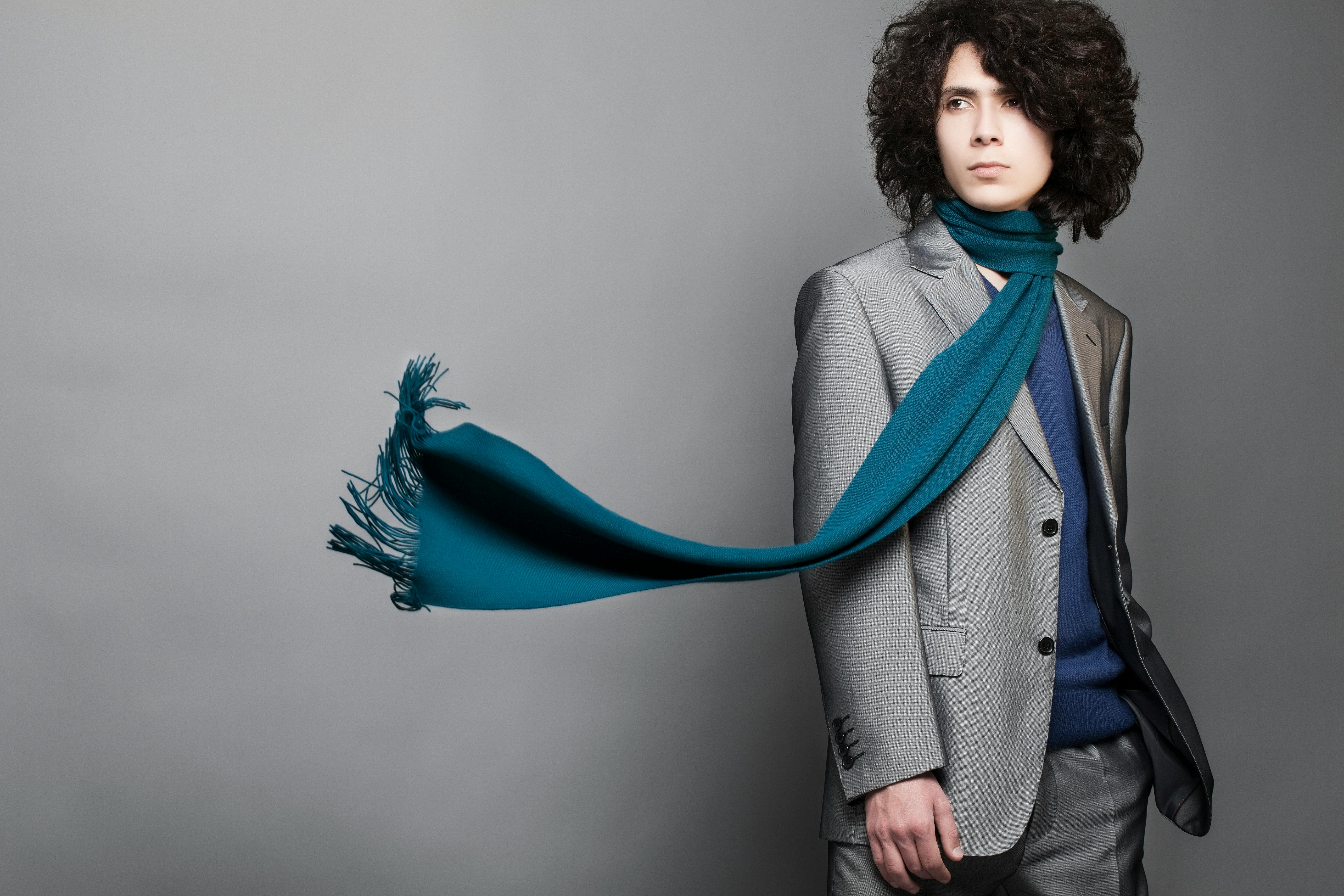 Fashionable man in gray suit with blue scarf in studio. Modern style and elegance.