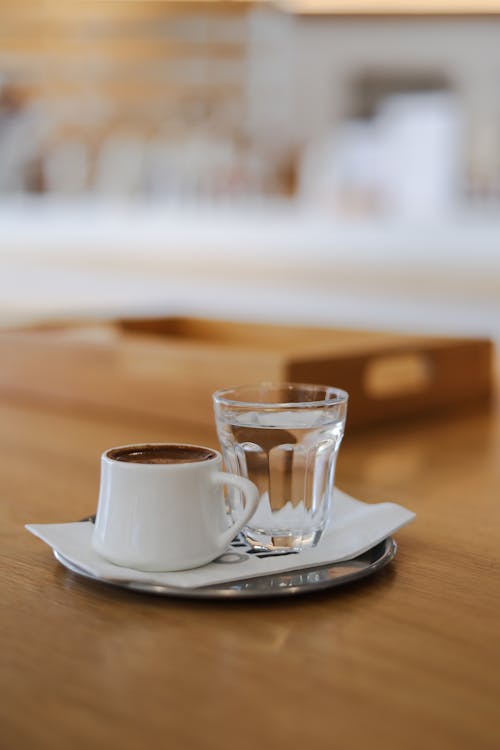 Drinking Glass and White Ceramic Cup on Brown Wooden Surface