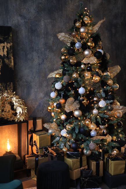 Beautifully decorated Christmas tree with elegant ornaments, lights, and presents in a cozy room.