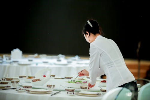 Woman Preparing Dish on Table