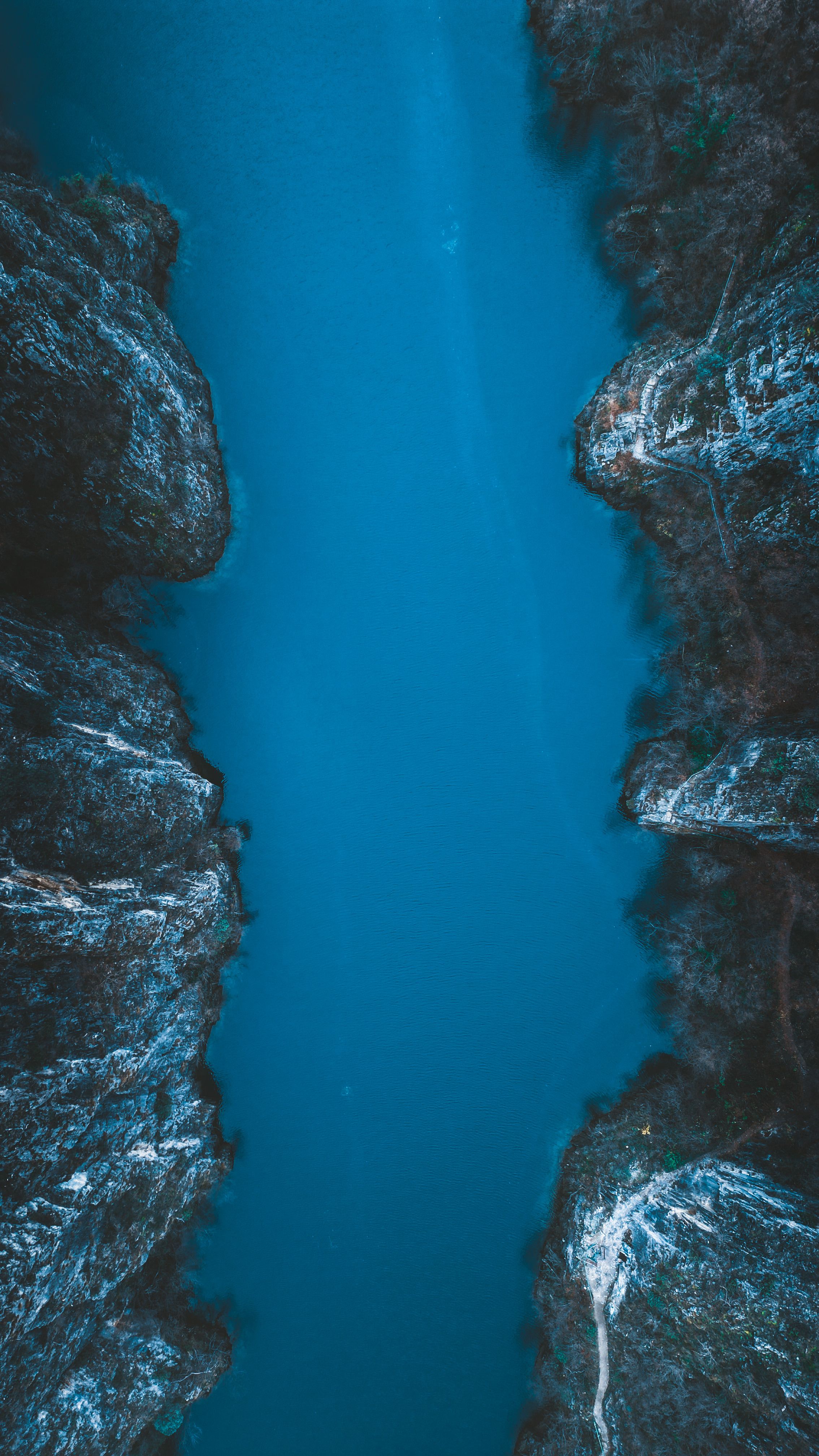 Stunning aerial view of a calm river gorge surrounded by rugged cliffs.