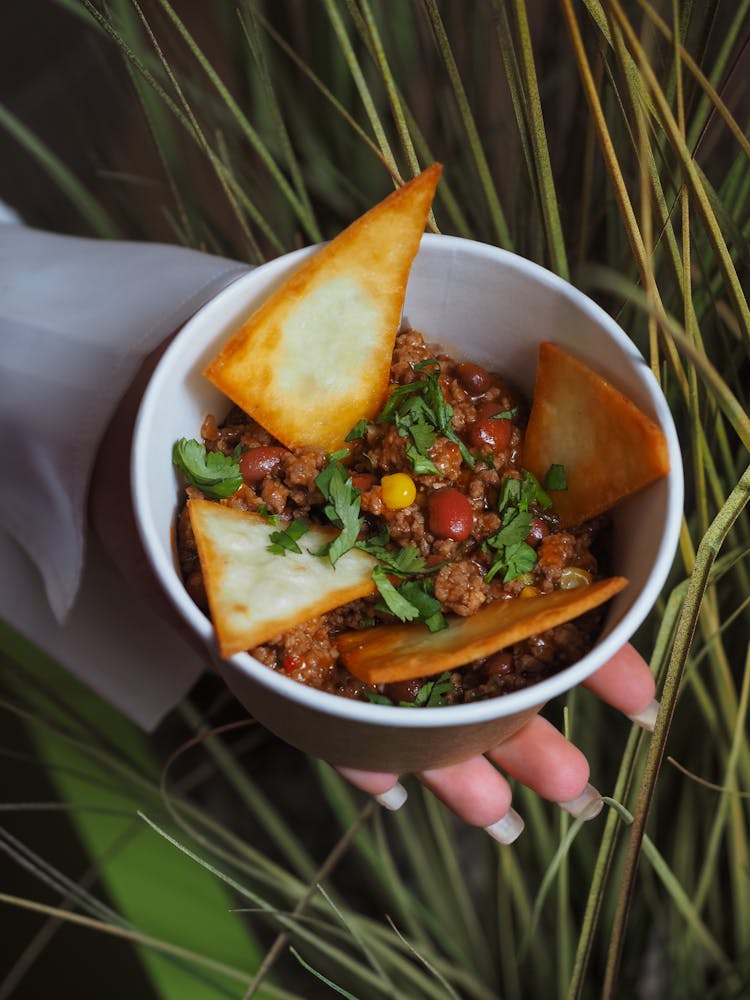 Hand Holding A Bowl With Chilli Con Carne