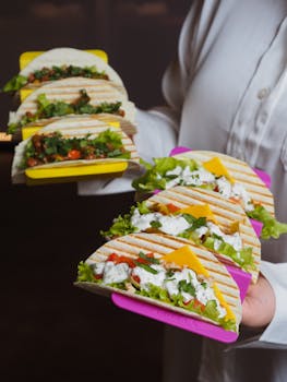 Mouth-watering tacos with fresh ingredients held by person in white shirt, perfect for food lovers.
