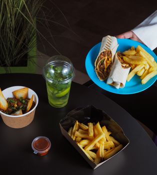 Delicious Mexican platter featuring burrito, fries, and refreshing lemonade.