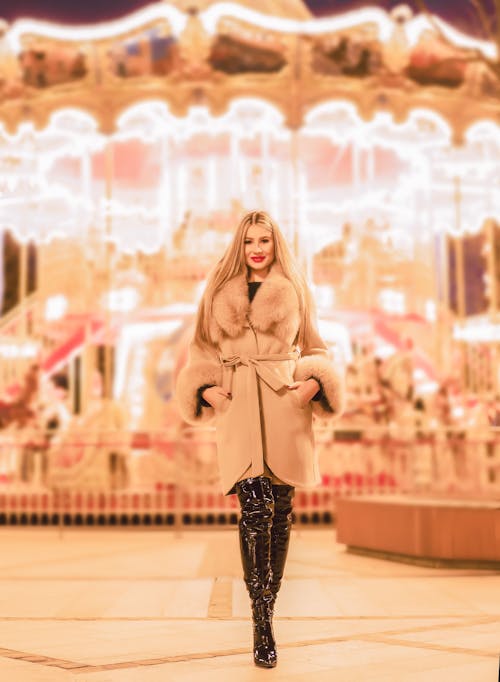A Woman in Fashionable Outfit Standing Near a Carousel