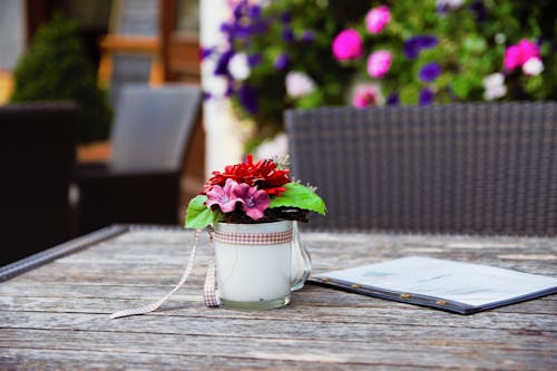 Red and Pink Artificial Flower Table Decor on Brown Wooden Table Shallow Focus Photography