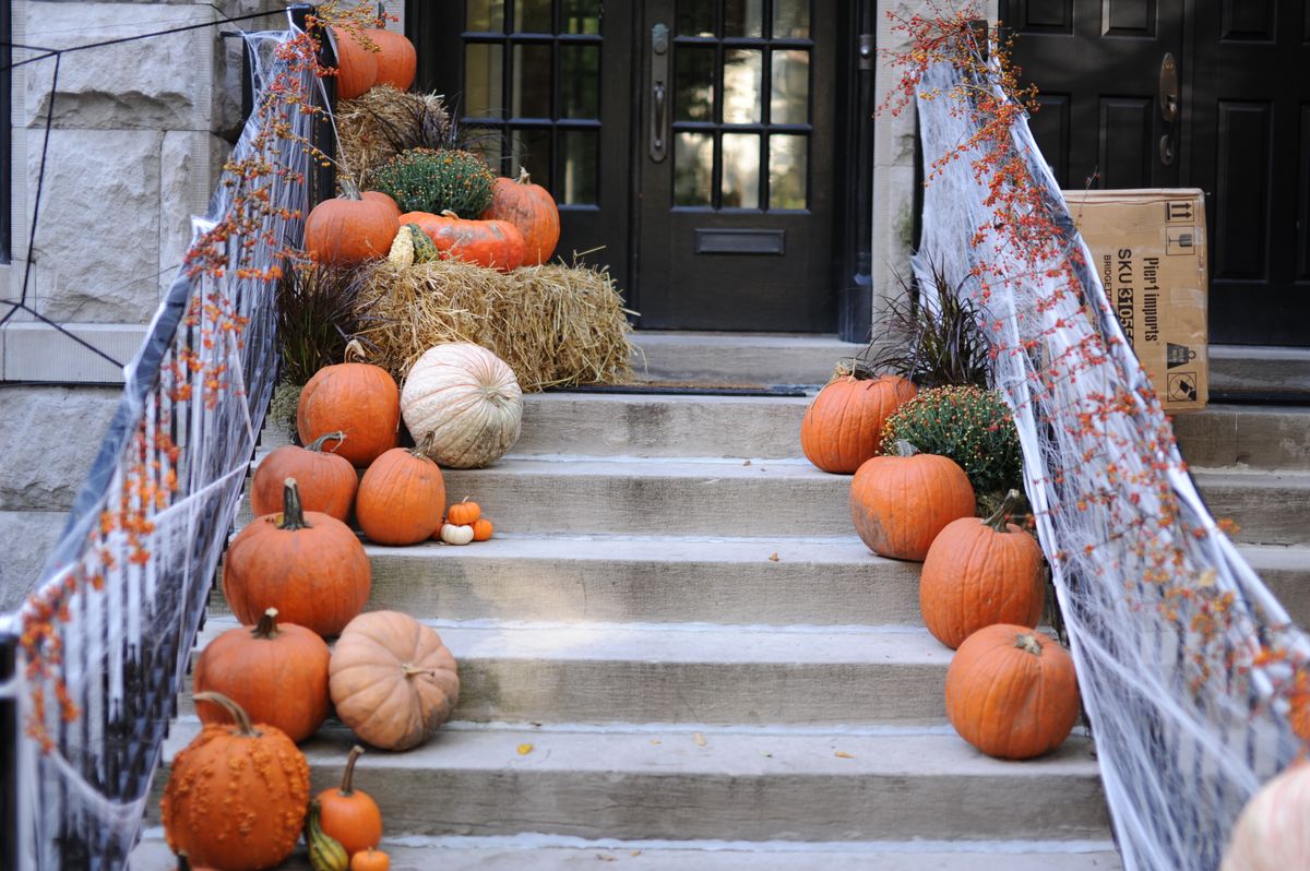 A front porch decorated with pumpkins and spider webs, celebrating Halloween and fall season. Stock Photo.
