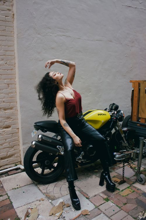 Free Woman posing confidently on a yellow Ducati motorcycle outdoors, showcasing fashion and style. Stock Photo