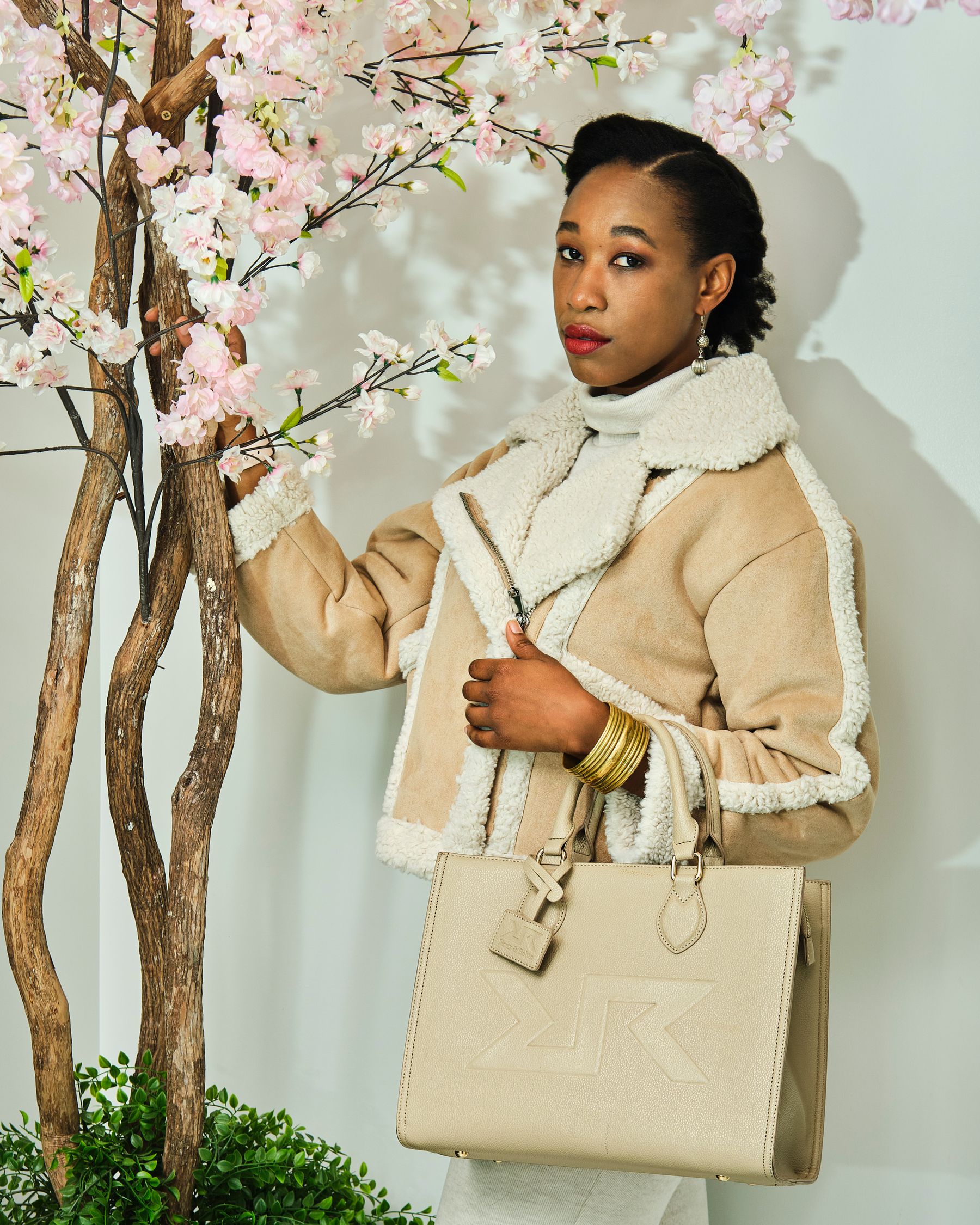 Woman in a refined beige outfit carrying a handbag in a softly lit fashion setting