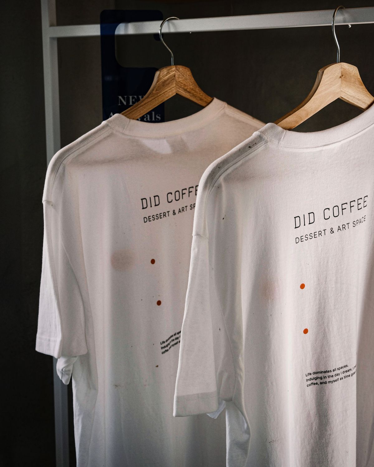 Two white printed t-shirts hanging on wooden hangers