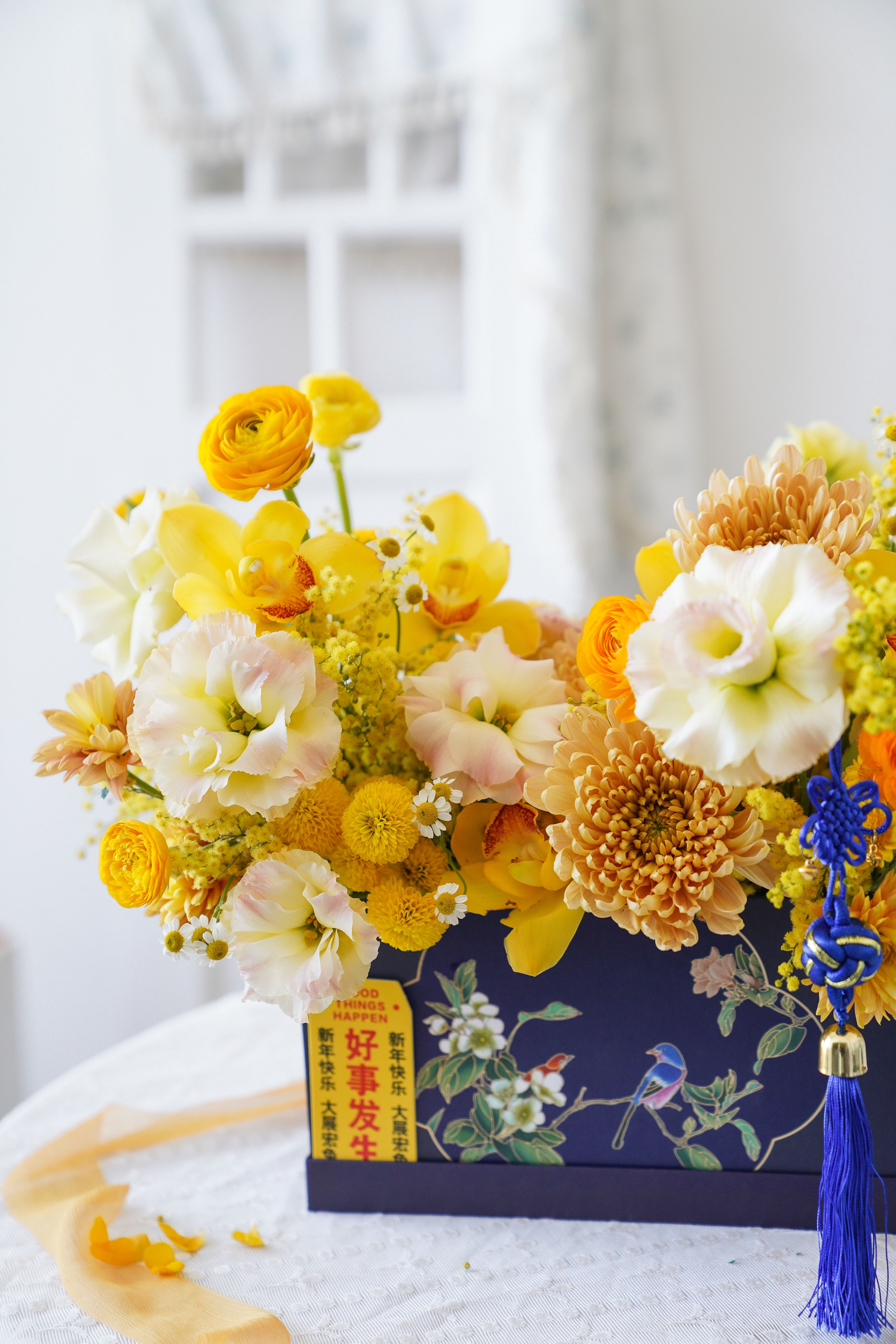 Bright yellow and white floral arrangement in a decorative box, indoors.