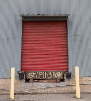 Red roller door at an industrial shipping ramp with corrugated metal wall.