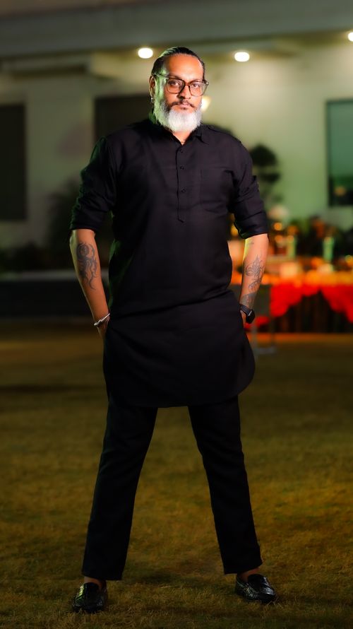 Free Bearded man in black clothing with a confident stance outdoors at night. Stock Photo