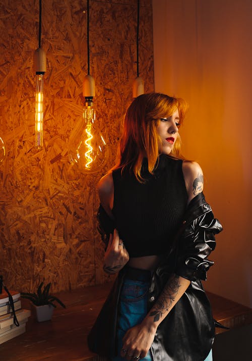 Woman in Jacket Posing near Light Bulbs near Wall