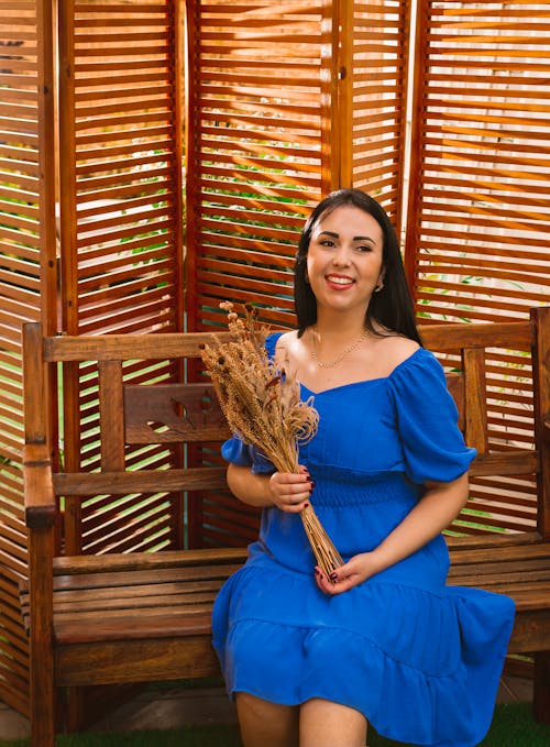 A Woman in Blue Dress Sitting on a Wooden Bench