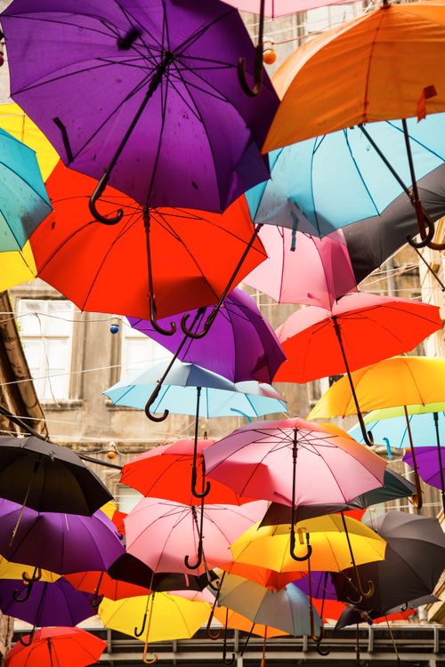 Free Vibrant display of multi-colored umbrellas hanging outdoors in daylight. Stock Photo