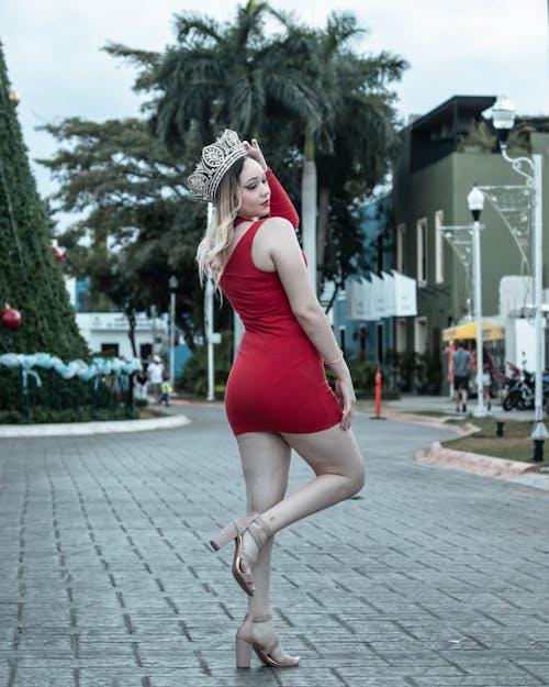 Woman in Crown and Red Dress Posing on Street