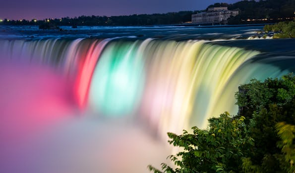 Stunning long exposure shot of Niagara Falls illuminated at night, showcasing colorful flowing water and mist. by James Wheeler