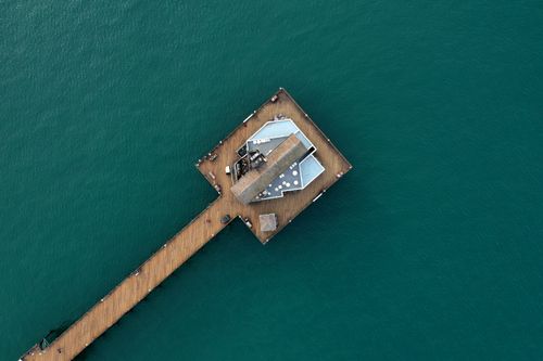 Free Aerial shot capturing Oceanside Pier extending into the vibrant blue ocean waters. Stock Photo