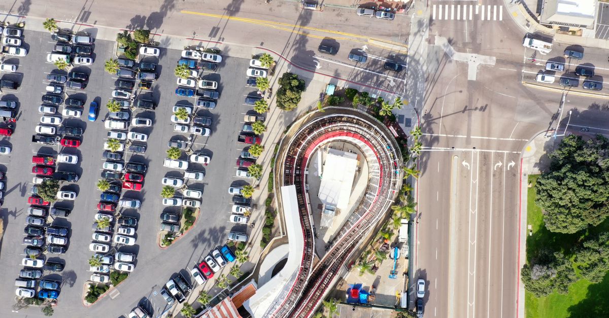 Aerial view of a parking lot, roads, and a unique curved structure in San Diego.