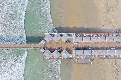 Free Overhead view of a beach pier with cars, featuring waves and sandy shoreline in San Diego, CA. Stock Photo