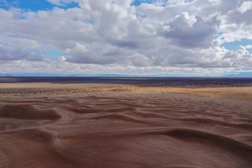 Free A captivating view of Beatty's desert dunes with a dramatic cloudy sky overhead. Perfect for travel and nature themes. Stock Photo
