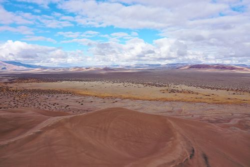 Free Expansive aerial view of a remote desert landscape with dunes and arid terrain in Nevada under a partly cloudy sky. Stock Photo